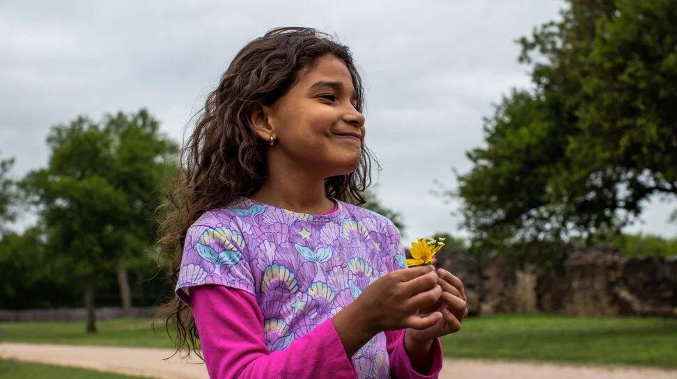 Duiliana, a 8-year-old refugee holds a small bouquet of flowers that she picked.