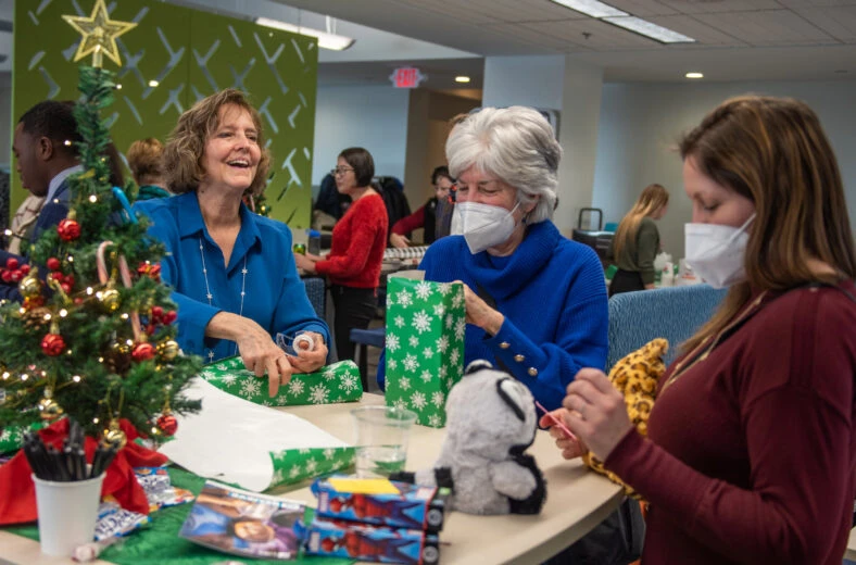 Three women wrapping gifts at Hope for the Holidays event.